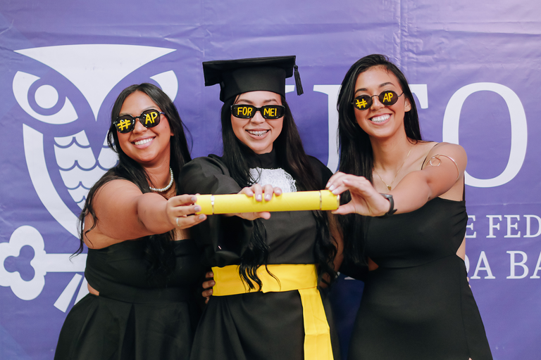 Imagem de formanda com duas amigas durante colação de grau da UFOB