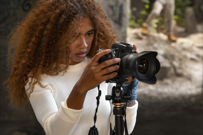 Imagem de estudante negra segurando câmera fotográfica na mão