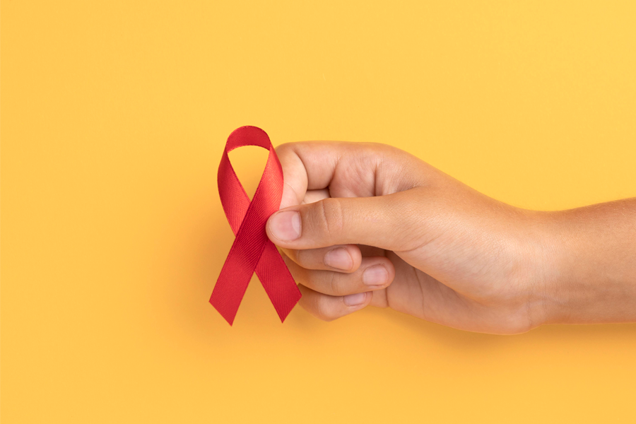 Arte em fundo amarelo com uma mão segurando um laço vermelho