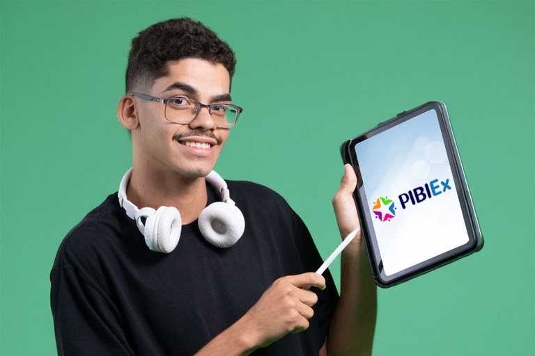 Imagem de estudante da UFOB com tablet na mão e apontando para a tela do equipamento onde está a marca do Pibiex