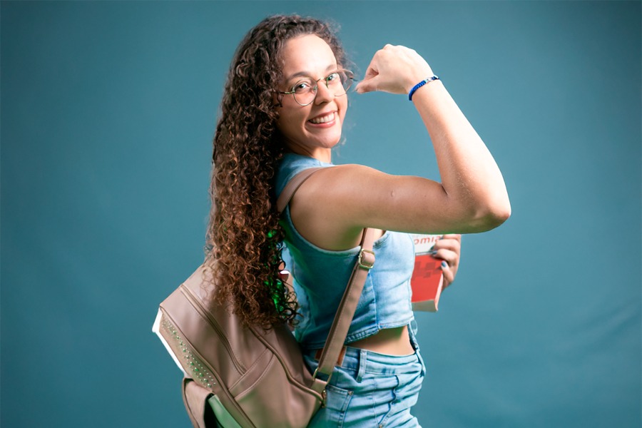 Imagemem fundo azul de estudante fazendo o gesto de força como braço