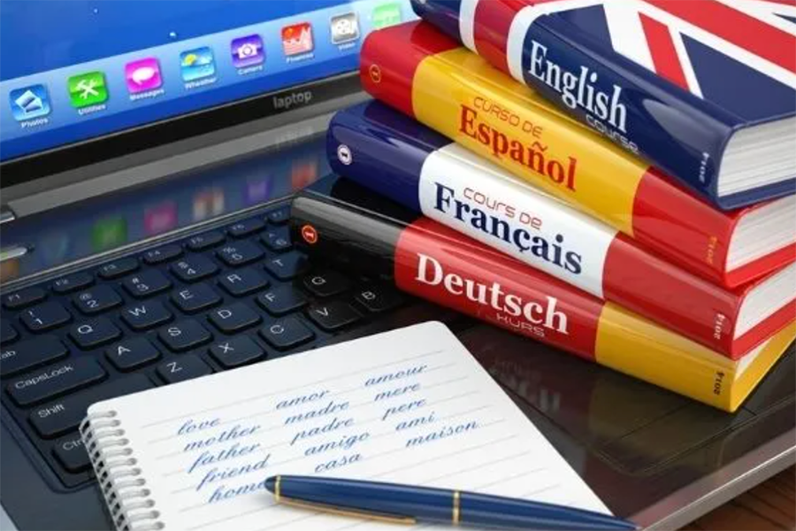 Imagem de notebook com dicionários das línguas inglesa, espanhola, alemã e francesa 