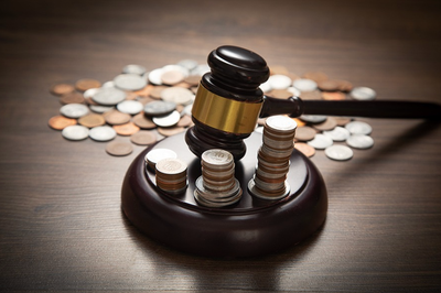 Imagem do martelo da justiça cercado de moedas em referência ao sistema tributário