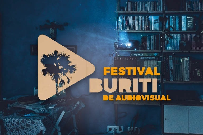 Imagem de estante com livros e bancada com computador ao fundo com marca do Festival Buriti à frente