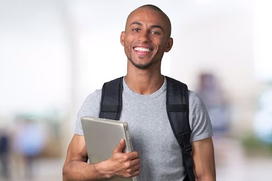Imagem de estudante negro com livro na mão e mochila