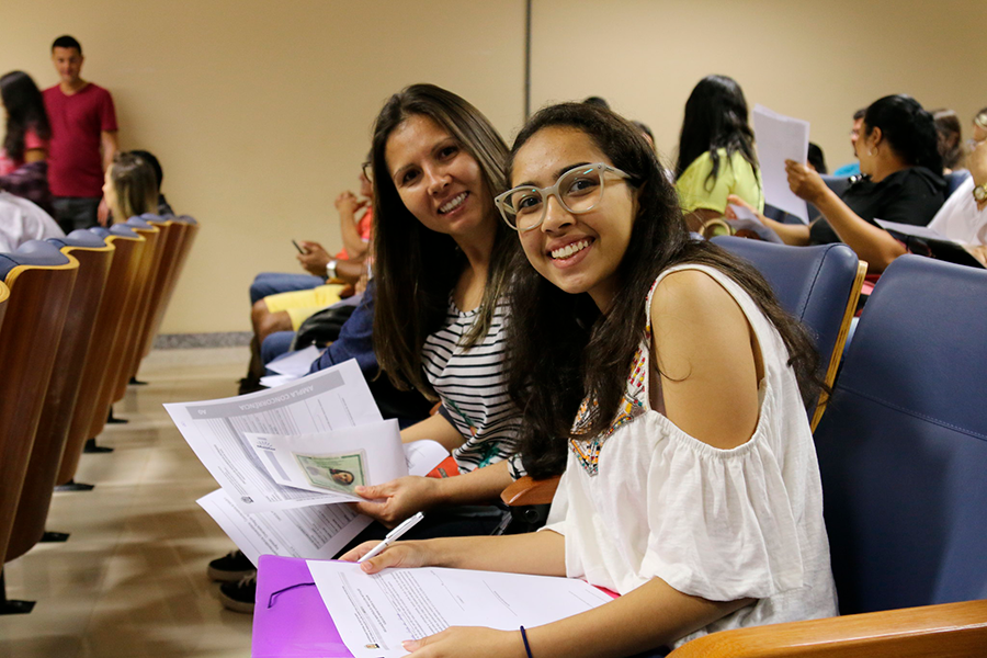 Imagem de estudantes sentadas e sorrindo no auditório durante a matrícula na UFOB